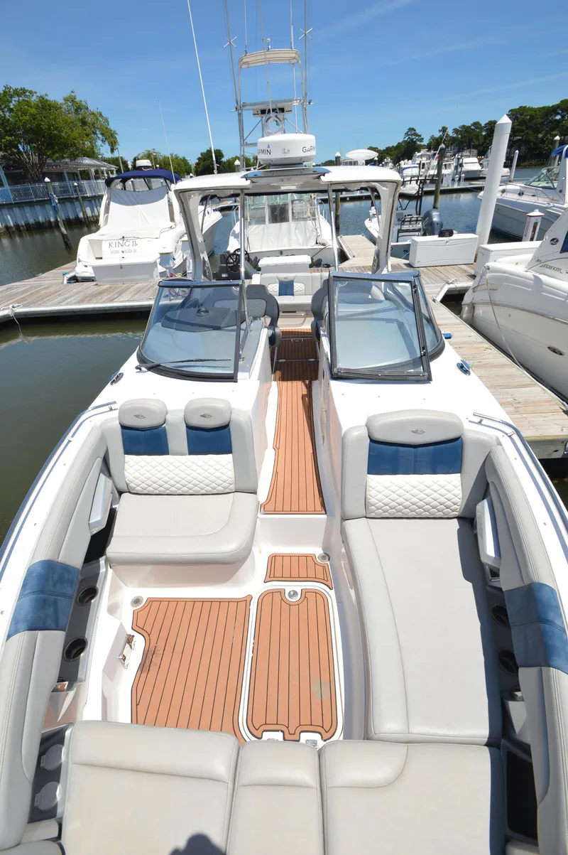 Slide: The Image of 2013 Chaparral 327 SSX boat with spacious seating and sleek design at a marina. - 19