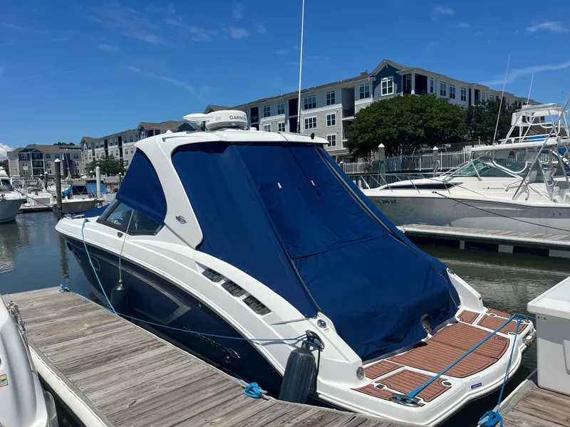 Slide: The Image of 2013 Chaparral 327 SSX boat docked, covered with blue canvas, near waterfront buildings. - 3