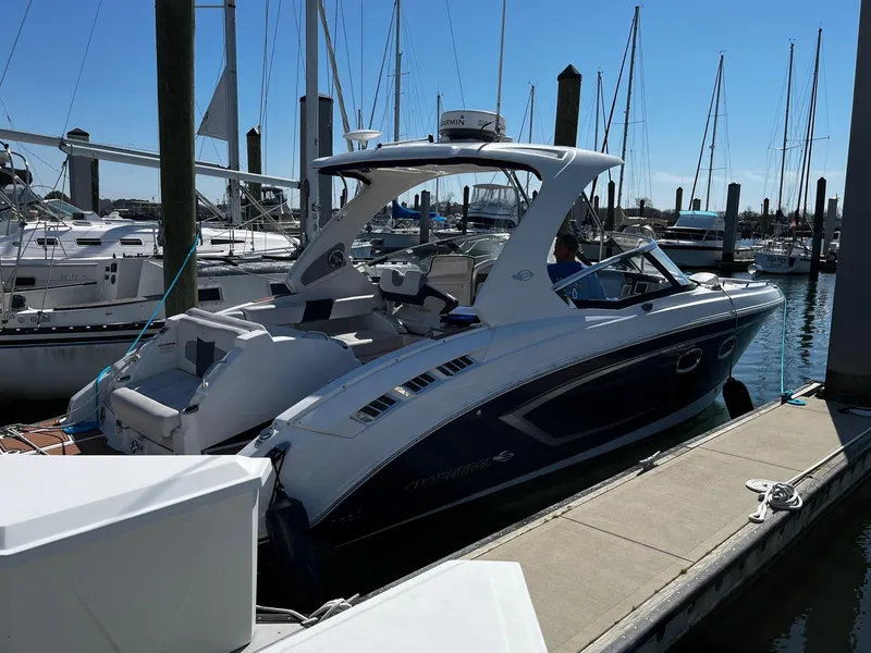 Slide: The Image of 2013 Chaparral 327 SSX boat docked at a marina with sailboats in the background. - 41
