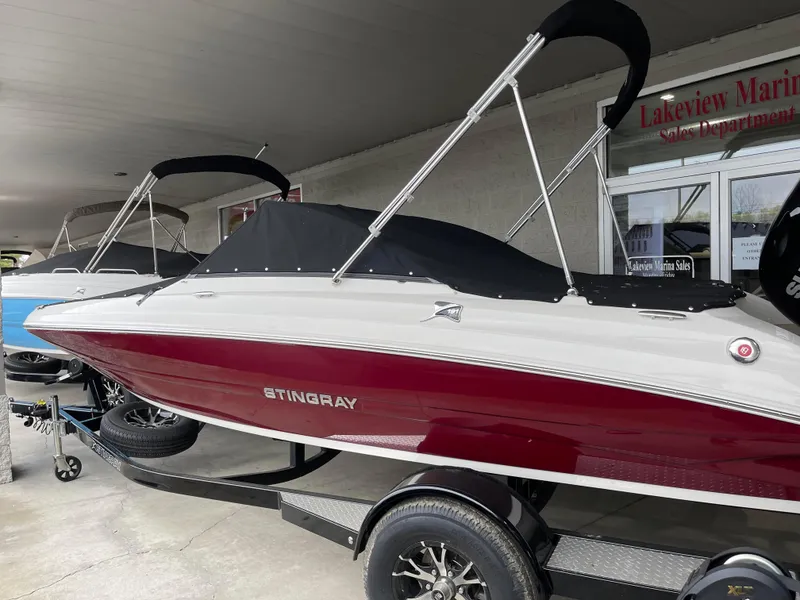 Slide: The Image of 2024 Stingray 191 DC boat in showroom, red and white exterior, covered, on trailer. - 21