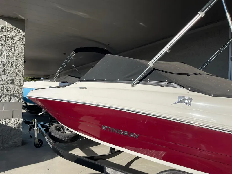 Slide: The Image of 2024 Stingray 191 DC boat with red and white exterior under a shelter. - 27
