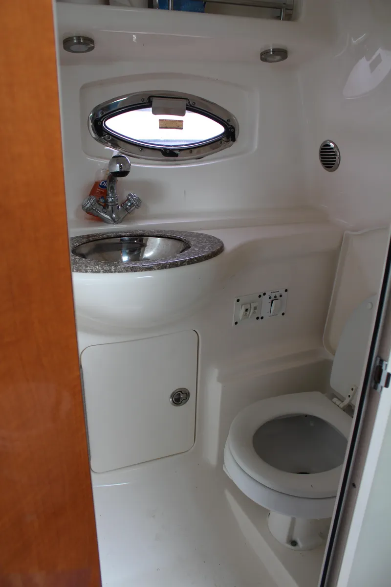 Slide: The Image of 2008 Chaparral Signature 290 boat bathroom with sink, toilet, and porthole window. - 44