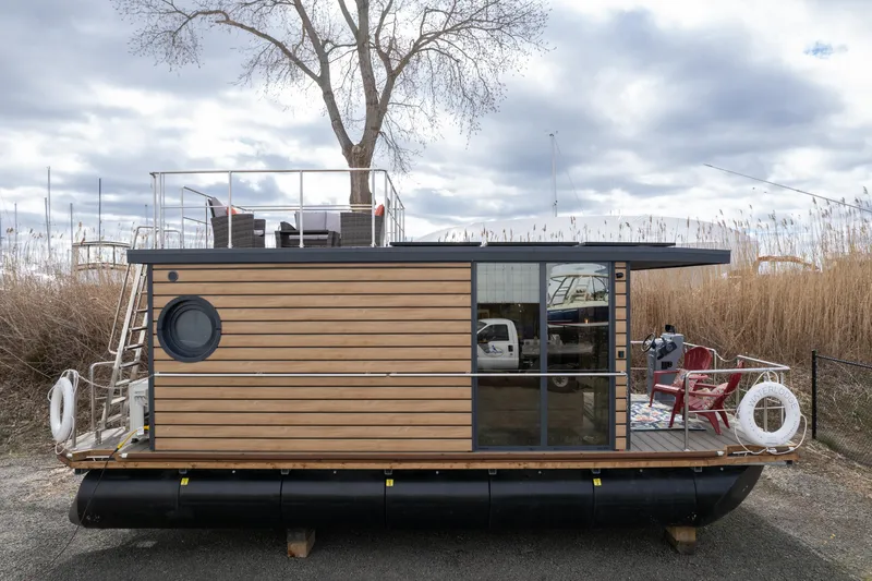Slide: The Image of 2024 Waterlodge Apart M houseboat with wooden exterior and rooftop deck. - 12