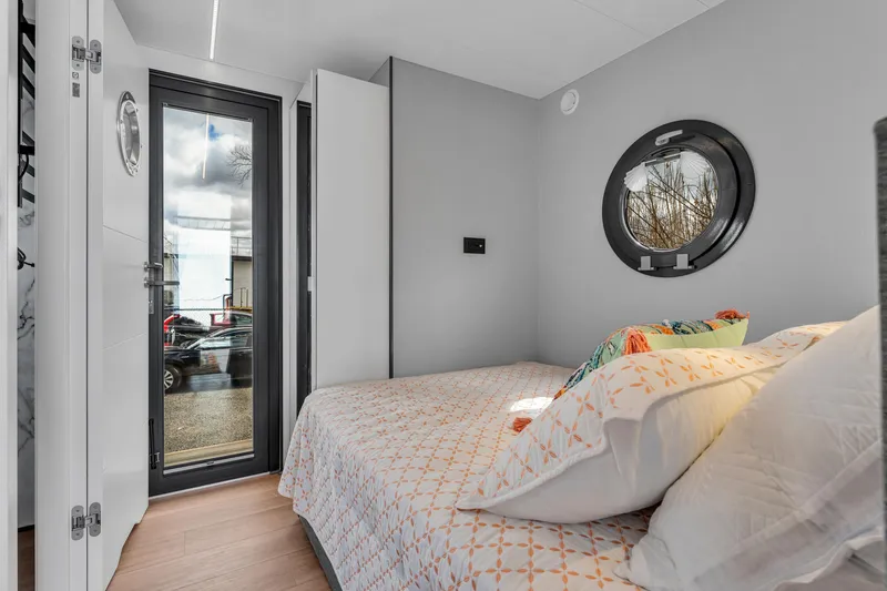 Slide: The Image of Modern bedroom in Waterlodge Apart M 2024 with cozy bed and porthole window. - 24