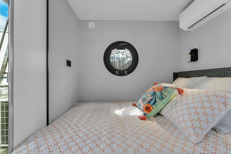 Slide: The Image of Cozy bedroom in 2024 Waterlodge Apart M with porthole window and colorful pillows. - 26