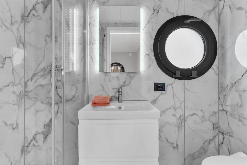 Slide: The Image of Modern bathroom in 2024 Waterlodge Apart M with marble walls and round window. - 27