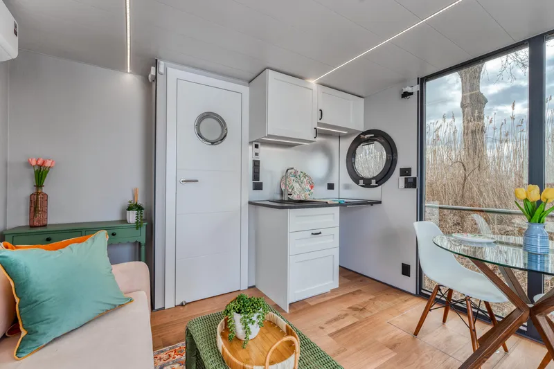 Slide: The Image of Modern Waterlodge Apart M 2024 interior with kitchenette, cozy seating, and large windows. - 32