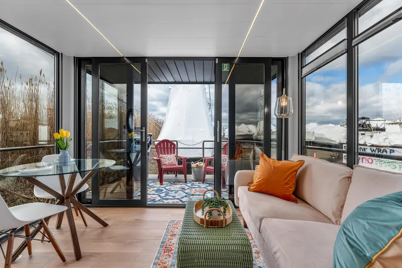 Slide: The Image of Modern interior of Waterlodge Apart M 2024 with glass doors, cozy seating, and outdoor deck. - 4