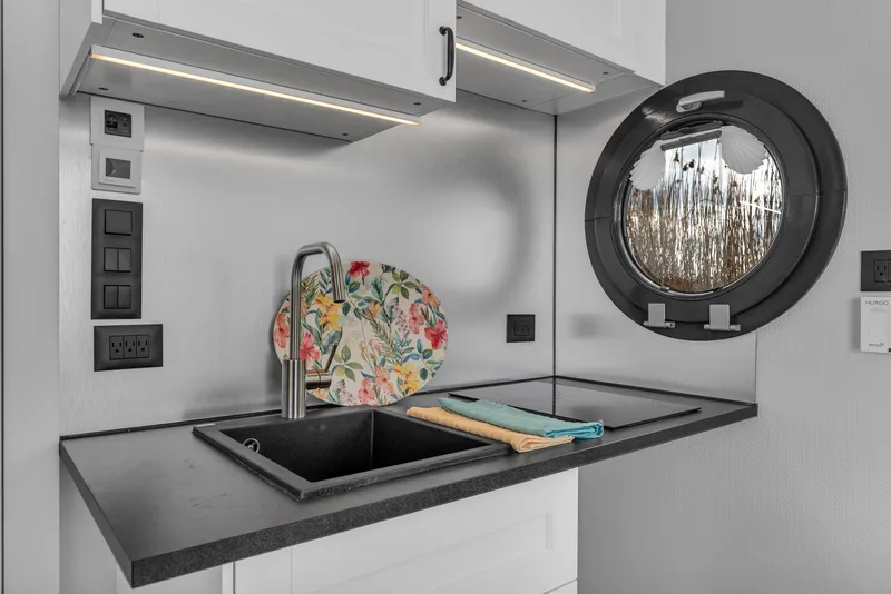 Slide: The Image of Modern kitchen sink area in 2024 Waterlodge Apart M with porthole window and floral decor. - 7