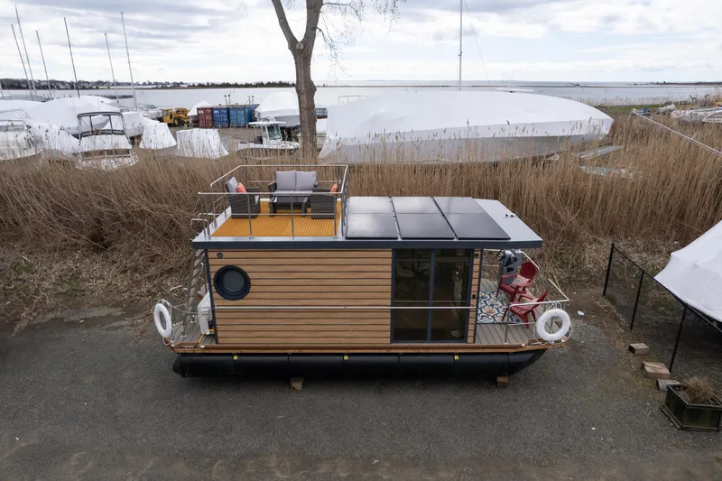 Slide: The Image of Waterlodge Apart M 2024 houseboat with wooden exterior and rooftop deck in a marina. - 8