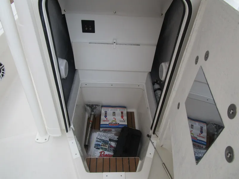 Slide: The Image of 2024 Ranger 2360 Bay boat storage compartment with equipment and manuals. - 34