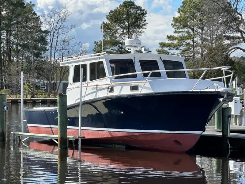 Slide: The Image of 2016 Custom Broad Creek 32 Downeast boat docked by trees and calm water. - 8