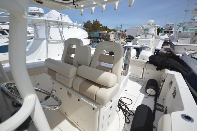 Slide: The Image of 2018 Boston Whaler 330 Outrage boat interior with cushioned seating and steering wheel. - 11