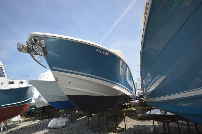 Slide: The Image of 2018 Boston Whaler 330 Outrage boat in storage, blue hull, side view. - 2