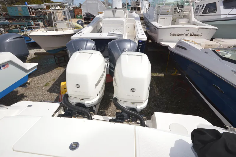 Slide: The Image of 2018 Boston Whaler 330 Outrage with twin outboard engines docked among other boats. - 22