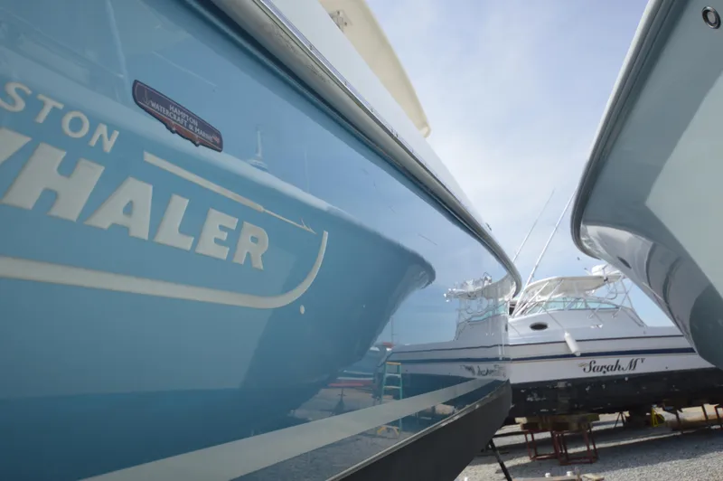 Slide: The Image of 2018 Boston Whaler 330 Outrage boat docked beside other vessels. - 4