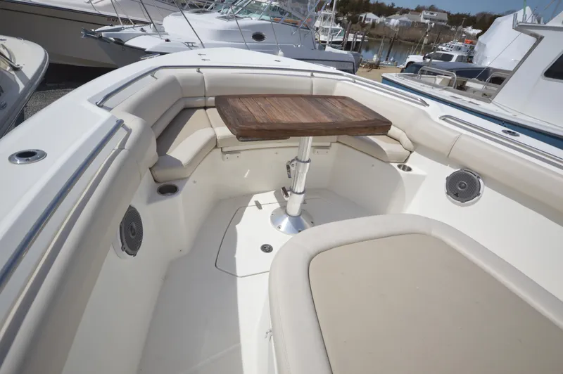 Slide: The Image of 2018 Boston Whaler 330 Outrage boat with cushioned seating and wooden table. - 6