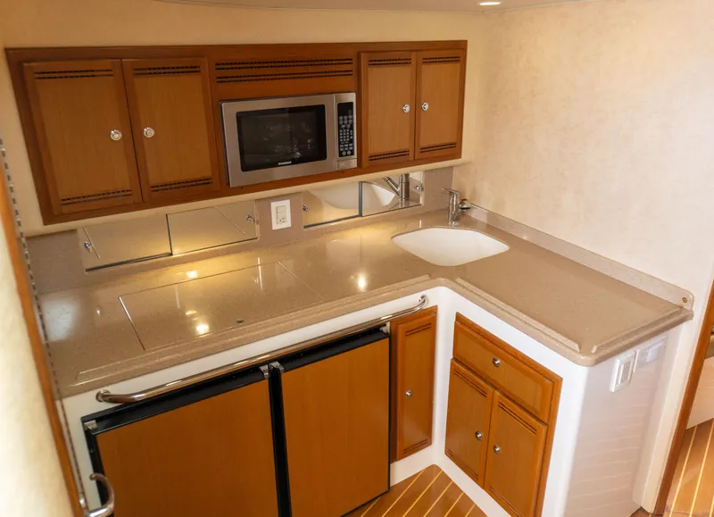 Slide: The Image of 2008 Cabo 38 Express boat kitchen with microwave, sink, and wooden cabinets. - 16