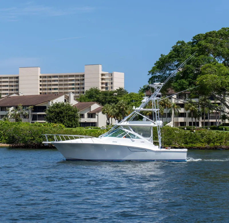 Slide: The Image of 2008 Cabo 38 Express boat cruising near waterfront buildings and lush greenery. - 35