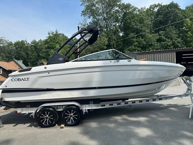 Slide: The Image of 2024 Cobalt R4 boat on a trailer, parked outdoors near trees and buildings. - 3
