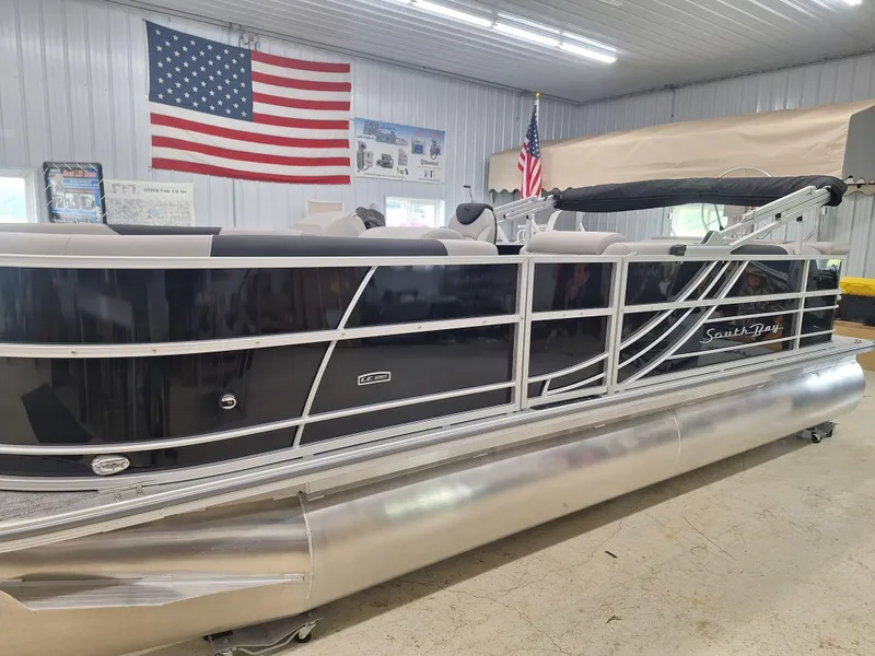 Slide: The Image of 2024 South Bay 222CRLE pontoon boat in showroom with American flag. - 10