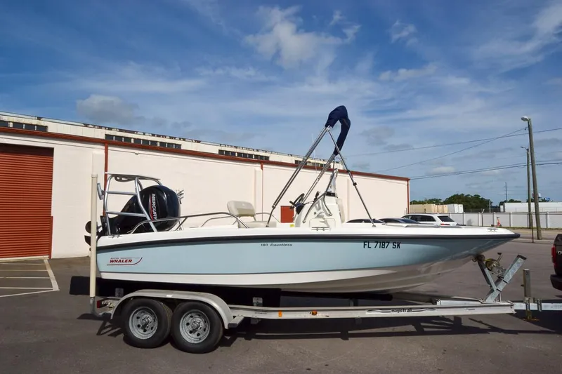 Slide: The Image of 2019 Boston Whaler 180 Dauntless boat on a trailer in a parking lot. - 2