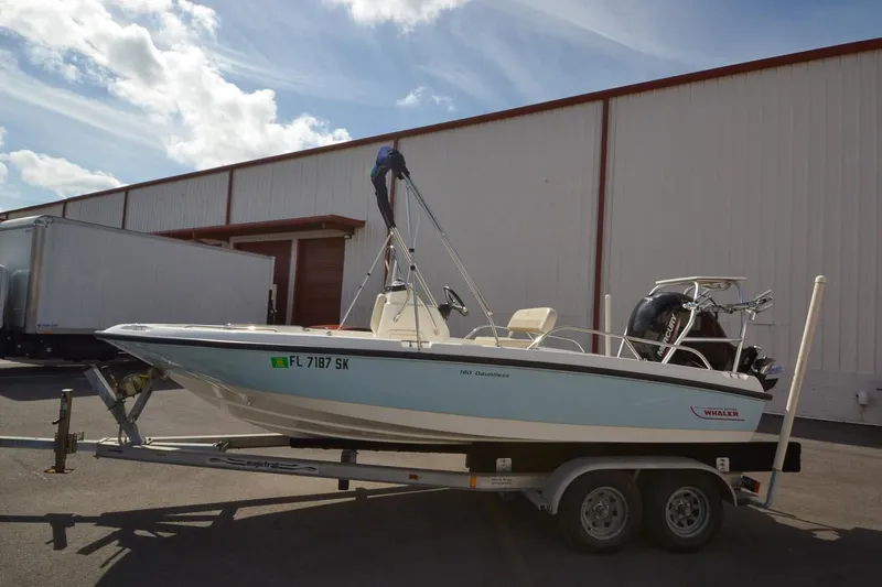 Slide: The Image of 2019 Boston Whaler 180 Dauntless boat on a trailer outside a warehouse. - 7