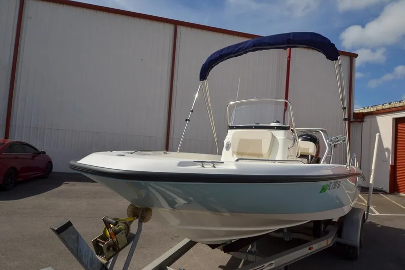 Slide: The Image of 2019 Boston Whaler 180 Dauntless boat on a trailer with a blue bimini top. - 8