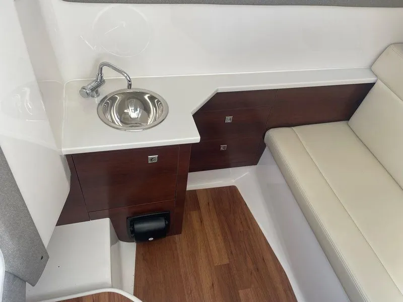 Slide: The Image of 2024 Chaparral 280 OSX interior with sink, wooden cabinetry, and cushioned seating. - 28