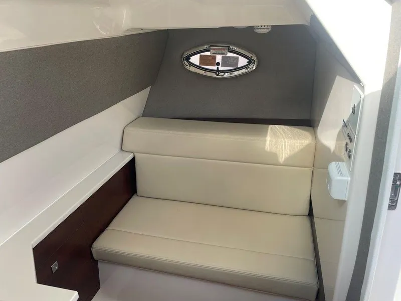 Slide: The Image of 2024 Chaparral 280 OSX cabin interior with beige seating and small window. - 29
