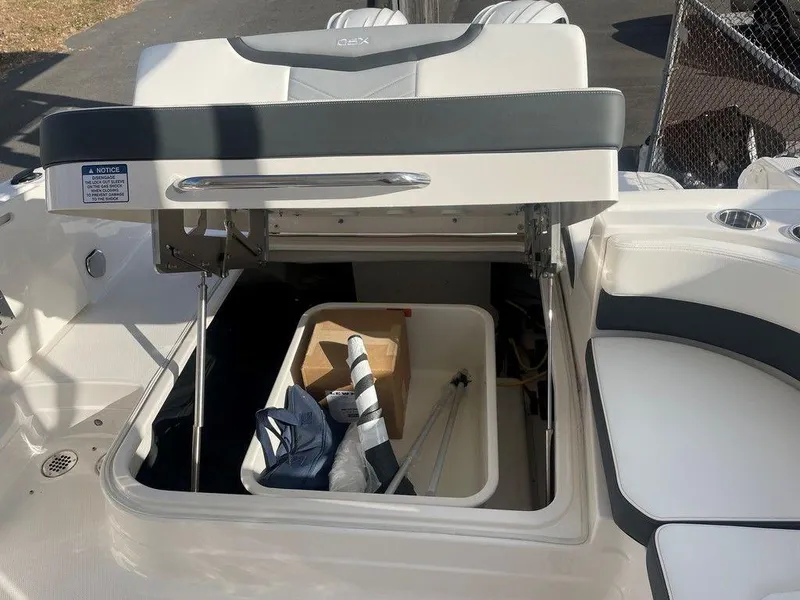 Slide: The Image of 2024 Chaparral 280 OSX boat storage compartment with open lid, showing interior items. - 35
