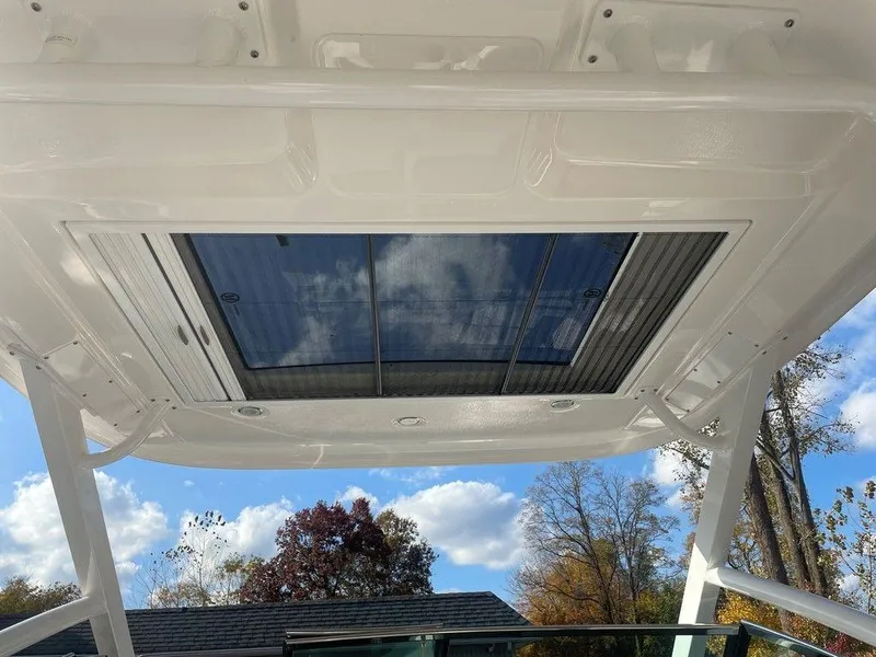 Slide: The Image of 2024 Chaparral 280 OSX boat roof with skylight, showcasing clear sky and trees. - 39