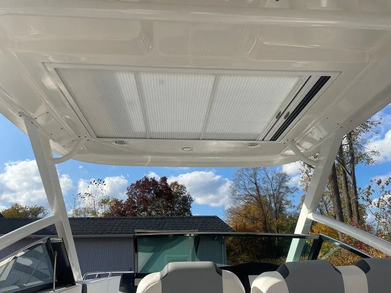 Slide: The Image of 2024 Chaparral 280 OSX boat interior with sunroof and seating, under a clear sky. - 40