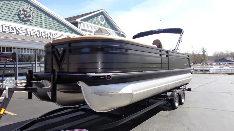 Slide: The Image of 2024 Viaggio Lago Z24U pontoon boat on trailer outside dealership. - 1