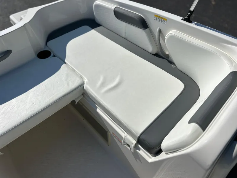 Slide: The Image of 2022 Bayliner Element E18 boat interior seating area with white and gray upholstery. - 16