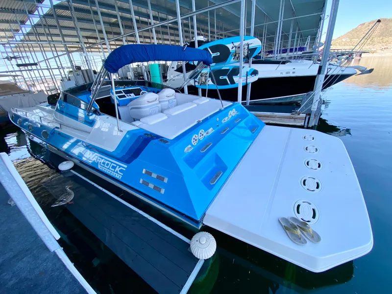 Slide: The Image of 1988 Warlock 37 Cat Cruiser boat docked in a marina, featuring a blue and white design. - 5