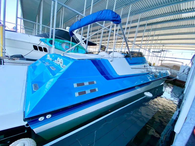 Slide: The Image of 1988 Warlock 37 Cat Cruiser in a marina, vibrant blue hull, covered dock. - 6