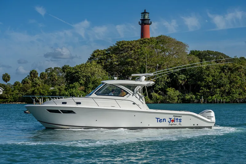 Slide: The Image of 2020 Pursuit OS 355 boat cruising near a lighthouse and lush greenery. - 12
