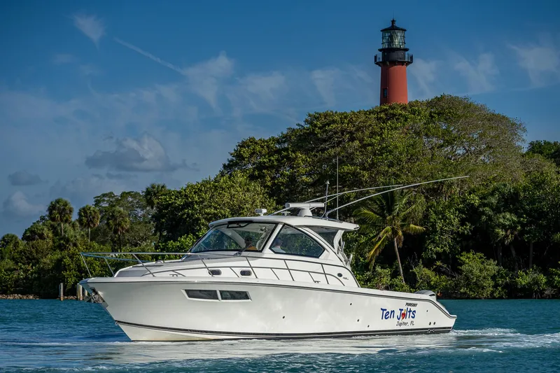 Slide: The Image of 2020 Pursuit OS 355 boat cruising near a lighthouse with lush greenery. - 14