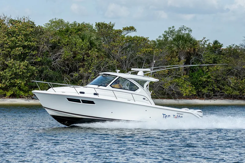 Slide: The Image of 2020 Pursuit OS 355 boat cruising on water near a forested shoreline. - 17