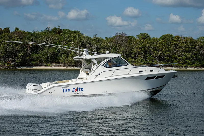 Slide: The Image of 2020 Pursuit OS 355 boat cruising on water near a forested shoreline. - 2