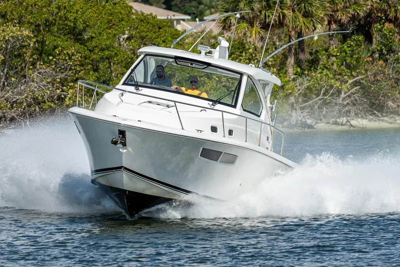Slide: The Image of 2020 Pursuit OS 355 boat cruising on water with lush greenery in the background. - 20