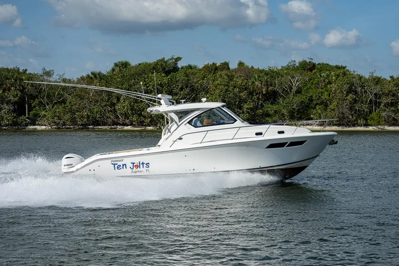 Slide: The Image of 2020 Pursuit OS 355 boat cruising on water near a forested shoreline. - 21