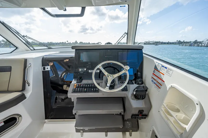 Slide: The Image of Helm station of 2020 Pursuit OS 355 boat with steering wheel and navigation screens. - 26