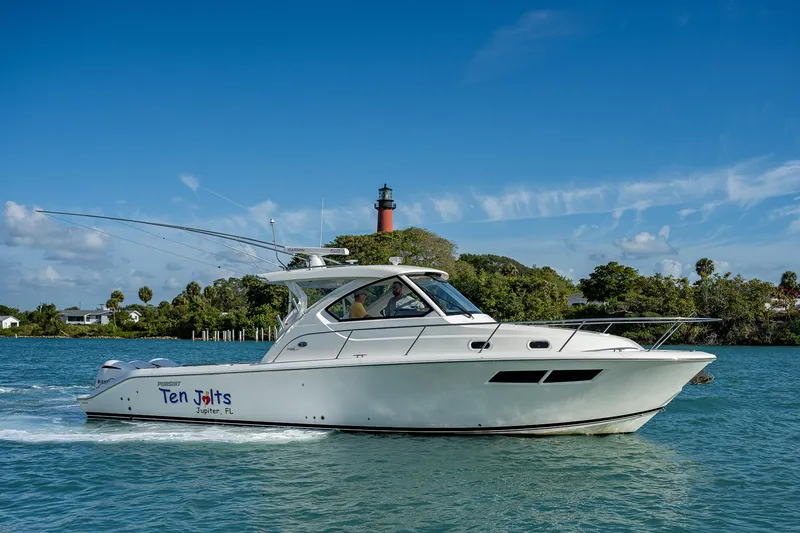Slide: The Image of 2020 Pursuit OS 355 boat cruising on a sunny day with a lighthouse in the background. - 4
