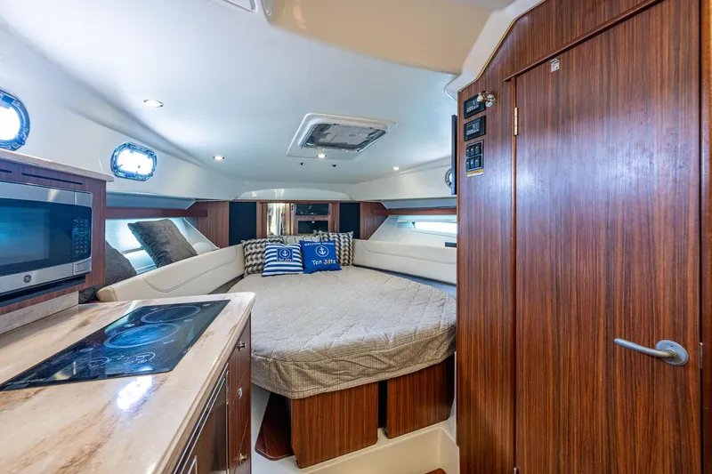 Slide: The Image of Interior cabin of 2020 Pursuit OS 355 boat with bed, microwave, and wooden cabinetry. - 43