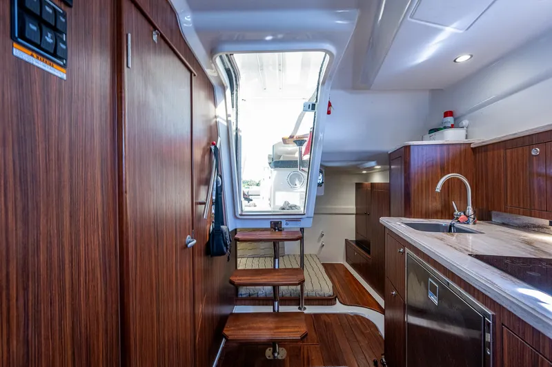 Slide: The Image of Interior of 2020 Pursuit OS 355 boat with wooden cabinetry and steps leading to deck. - 45