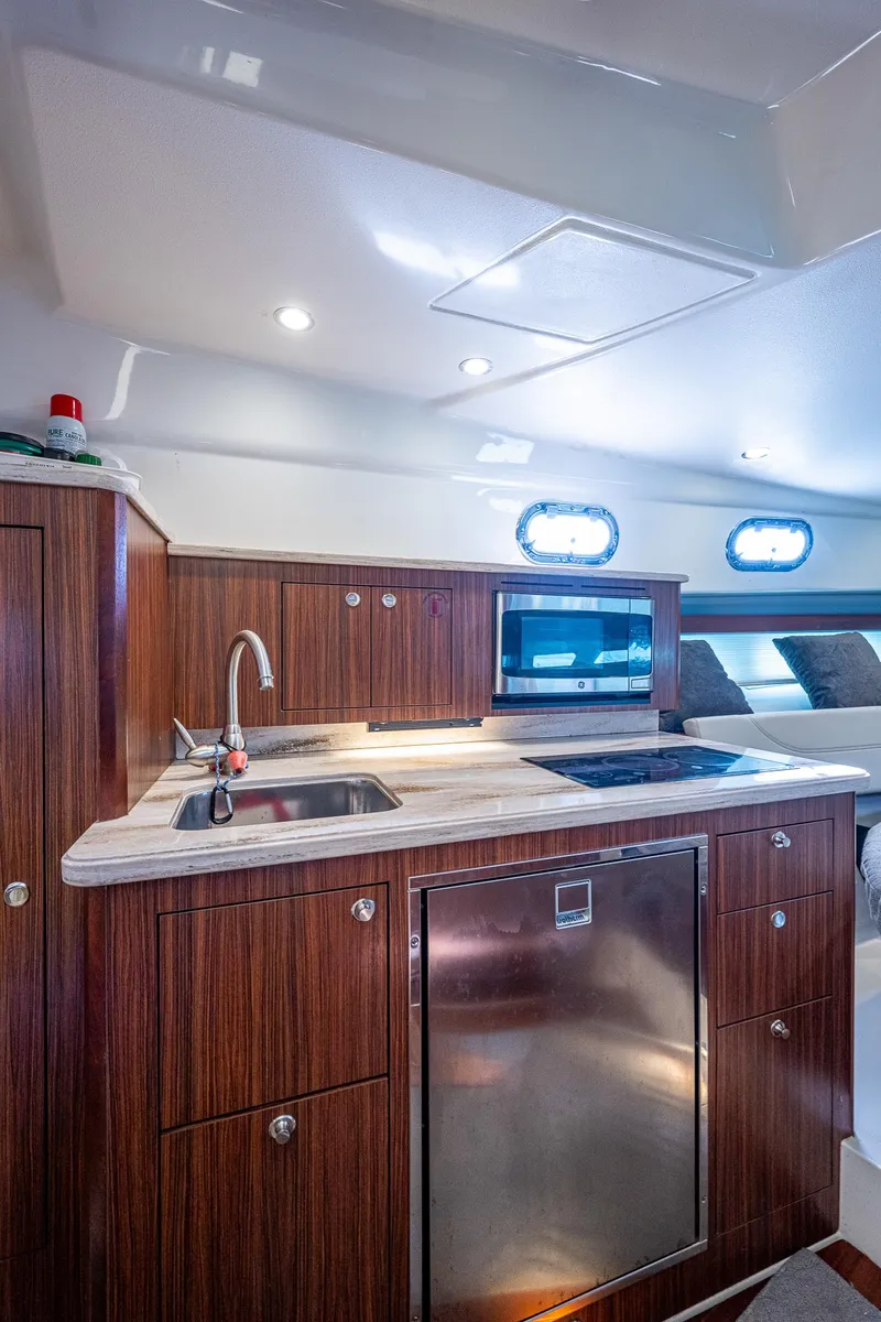 Slide: The Image of Modern kitchen area in 2020 Pursuit OS 355 boat with wood cabinetry and stainless steel appliances. - 46