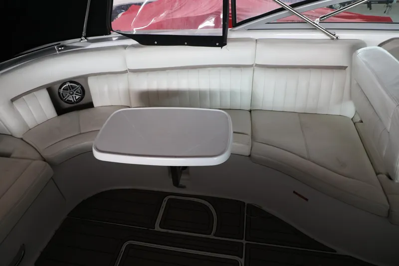 Slide: The Image of Interior of a 2006 Cobalt 323 boat with white leather seating and a table. - 9