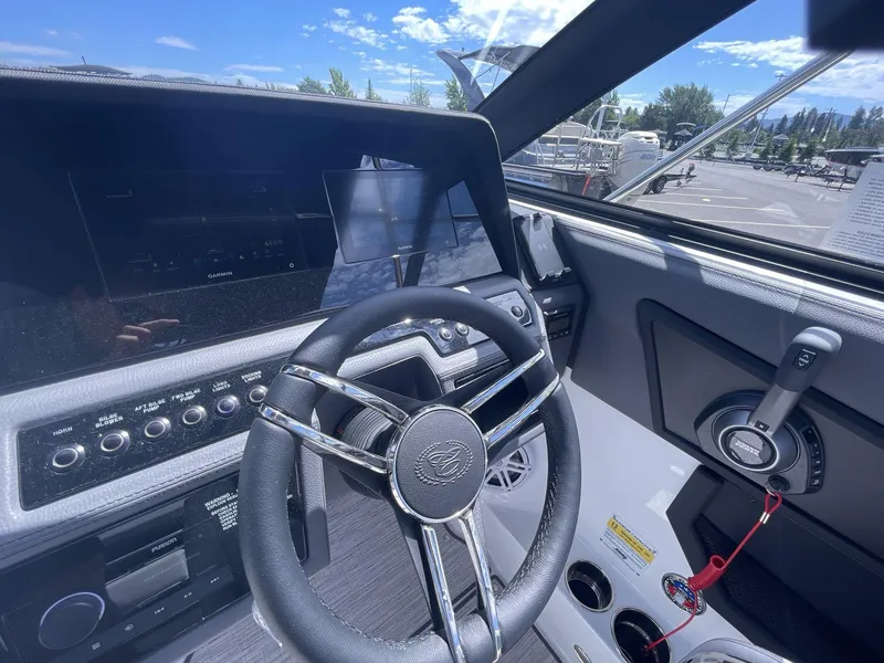 Slide: The Image of 2024 Cobalt R4 boat dashboard with steering wheel and control panel under clear blue sky. - 12